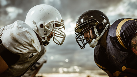 Two American football players looking at each other on a beginning of the match.
