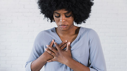 The woman holds her chest as she experiences a shortness of breath.